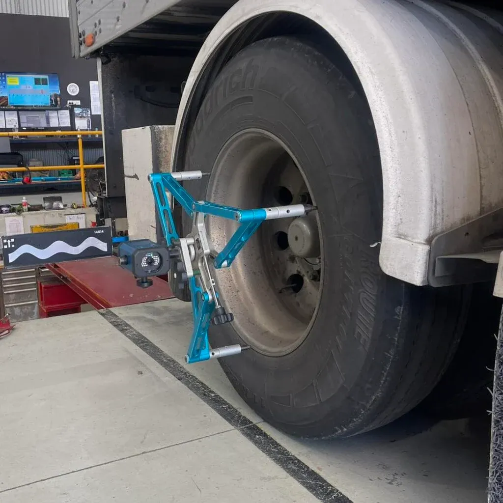 A vehicle service or repair shop, showing a heavy-duty truck wheel undergoing an alignment procedure.